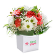 Lively and invigorating, this bouquet seems to capture the creative pulse of New Cross in bloom. Arrayed within a pristine square white gift bag, coral and peach-hued carnations unfurl in lush ruffled swathes, each blossom glowing with an understated vitality. White daisies, their lime-yellow centers radiant, scatter bursts of optimism throughout, much like unexpected art installations peppered across Deptford's streets. Sprigs of cloud-like baby's breath flicker between the petals, embodying a softness that soothes and lifts the spirit. Unopened purple-tipped buds lend a note of intrigue, as if the local area's energy is held in potential, waiting to unfold. All the blooms rest within a collar of deep green foliage, their sheen reflecting the vibrancy of New Cross's parks and communal gardens. Crafted into a generous and joyful rounded posey, the bouquet is perfect for birthdays, graduations, or simply to convey a message of hope and warmth. The elegantly simple gift bag, complete with white ribbon handles, is thoughtfully designed for moments of connection and delight-ready to be delivered from New Cross's local florists to homes, celebrations, or heartfelt reunions along the bustling high roads. Every detail is aglow in gentle light, offering a sensory reminder of the beauty and creativity that defines this unique London neighbourhood.