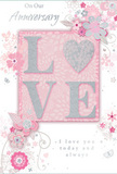 The anniversary card shown here captures the gentle charm of a pastel arrangement arriving on a quiet New Cross side street. At the centre, the word LOVE stands proudly in raised, tactile letters, coated with delicate blush-pink and pearlescent white glitter that shimmers softly. A dusting of silver along the letter edges adds a subtle sparkle, as though the word itself were dusted with starlight. Behind this focal point, the background is a soothing blush pink, smoothly graded so the colour deepens around the central motif and fades to a softer tone at the borders, much like a watercolour wash on fine card. Flowing around the central word is a graceful arrangement of stylised flowers and slender leaves, all drawn in fine white and soft grey lines. Each blossom is delicately rendered, with some petals lightly shaded and others barely outlined, creating an impression of airy movement. The florals curl and sweep outward, resembling the loose, organic shape of an anniversary bouquet designed by a skilled local florist. Subtle silver-foil touches glint here and there along the petals and tendrils, lending a refined, celebratory feel without overwhelming the pastel calm. Elegant script lettering carries warm anniversary wishes, placed above and below the central design in a way that frames rather than crowds it. The script is softly curved and coloured in muted grey, echoing the flowing lines of the vines. Altogether, the card radiates tenderness, grace, and quiet celebration-a paper expression of enduring love, much like a softly scented bouquet delivered to a cosy home in New Cross to honour a cherished milestone.